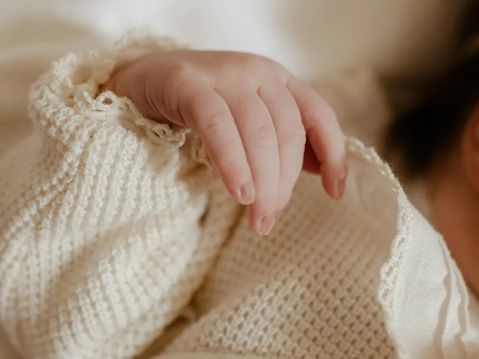 Eine Babyhand auf einer gestrickten Decke