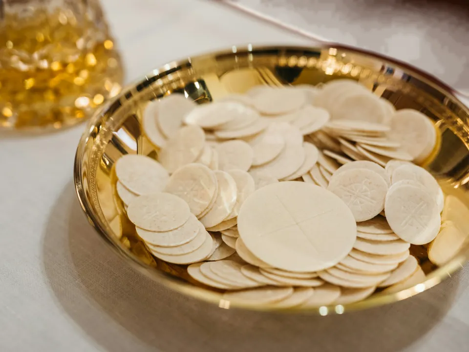 Hostien in einer goldenen Schale auf einem Leinentuch
